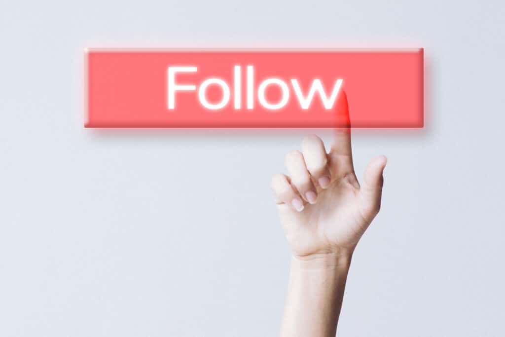Hand clicking follow button on social media