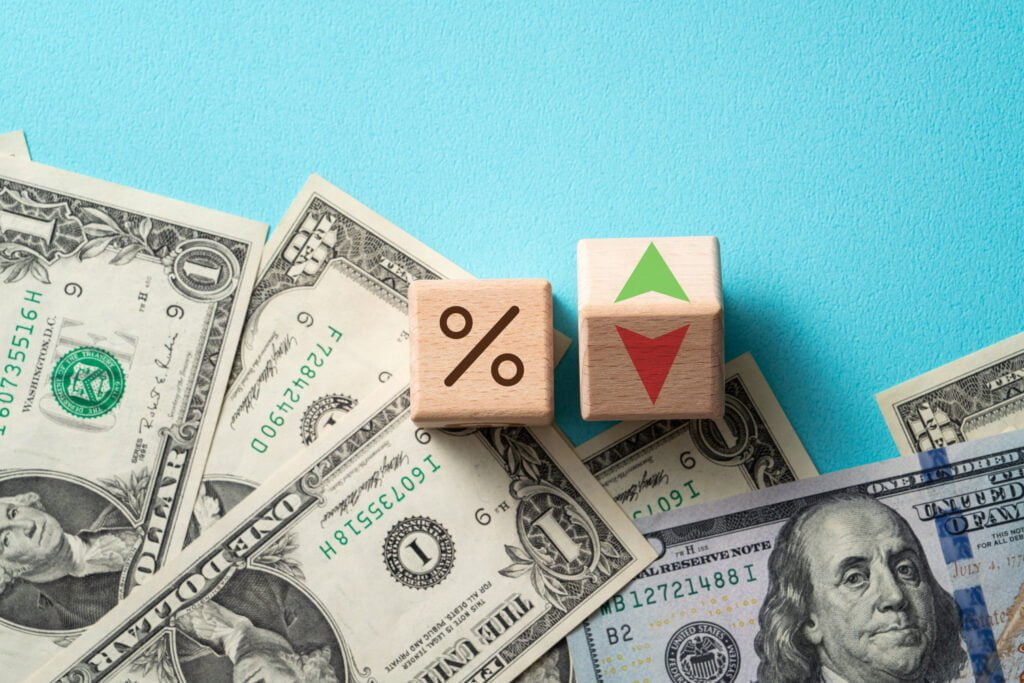 Wooden blocks with interest rate percent of bank with US dollars, financial world economy crisis design concept. การปรับอัตราดอกเบี้ยส่งผลอย่างไรต่อสกุลเงิน