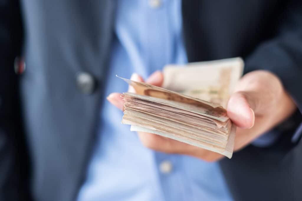 Businessman hand holding Thai Baht banknote stack. business, mon