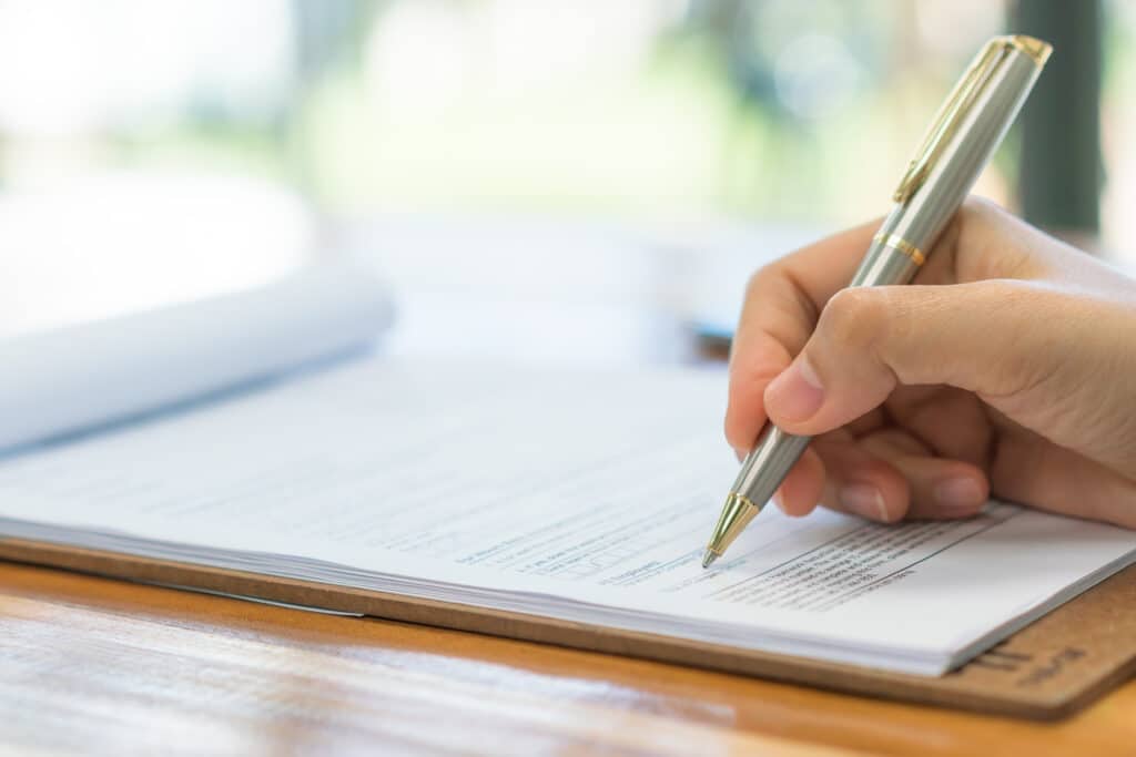 Hand with pen over application form . กรอกข้อมูลเทรด Forex